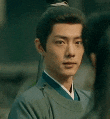 a man in a green robe is looking at a woman in a blue dress .