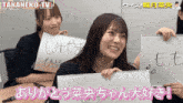two girls holding up signs that say takaneko-tv
