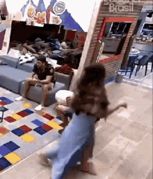 a woman is dancing in a living room with a sign that says brasil