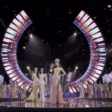 a woman in a crown stands on a stage in front of a large circle of lights
