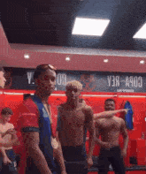 a group of men are standing in a locker room with a sign above them that says v3a-a903