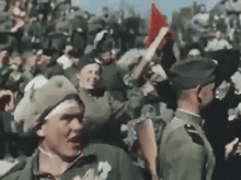 a group of soldiers are standing in a crowd holding up flags
