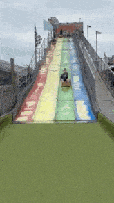 a man is riding down a rainbow colored slide at a theme park .