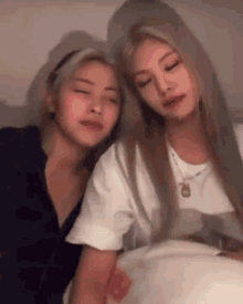 two young women are sitting next to each other on a bed .
