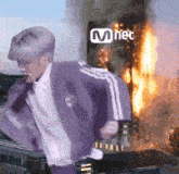 a man in a purple jacket is running in front of a fire .