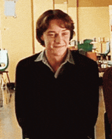 a young man wearing a black sweater is smiling