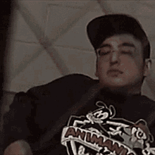 a man wearing a t-shirt that says ' animaniacs ' on it is sleeping on a bed