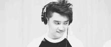 a black and white photo of a young man wearing headphones and smiling .