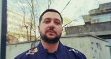 a man with a beard wears a blue jacket with a red bull logo on it