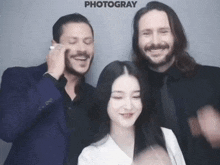 two men and a woman are posing for a photo with the word photogray in the corner