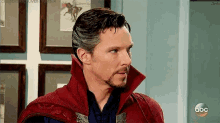 a man in a doctor strange costume is standing in front of a wall with pictures on it .