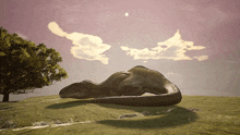 a statue of a dinosaur laying on top of a grass covered hill