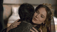 a woman in a tiara is hugging a man