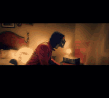 a man wearing a mask and a red jacket is sitting on a bed