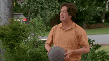 a man in an orange shirt holds a basketball