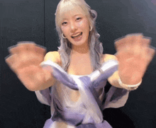 a woman in a purple dress is smiling and holding her hands up