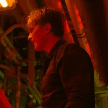 a man in a dark room with a red light behind him
