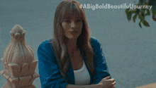 a woman in a blue jacket sits with her arms crossed and a big bold beautiful journey written on the bottom