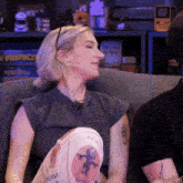 a woman is sitting on a couch with her eyes closed wearing a t-shirt that says " raw "