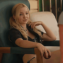 a woman sits in a chair with her hand on the armrest