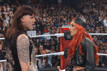 a man and a woman are standing in a wrestling ring looking at each other .