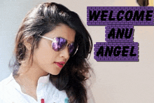 a woman wearing sunglasses stands in front of a sign that says " welcome and angel "