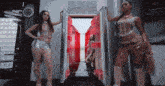 two women standing in front of an open refrigerator with a red light