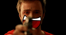 a man is pointing a gun at the camera while wearing a red mask .