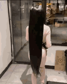 a woman with very long black hair is standing in front of a door