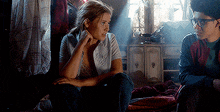 a boy and a girl are sitting on the floor in a dark room