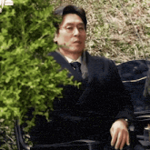 a man wearing glasses and a suit sits in a chair