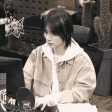 a woman is sitting in front of a computer with a microphone .