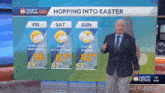 a weatherman stands in front of a screen that says ' hopping into easter ' on it