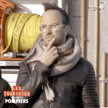 a man wearing glasses and a scarf with the words les touristes mission pompiers written on the bottom