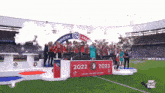 a group of people standing on a podium with the year 2022 and 2023 written on it