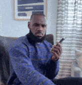 a man in a blue sweater is looking at his phone