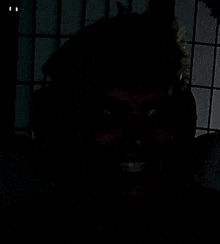 a person is smiling in the dark and looking at the camera .