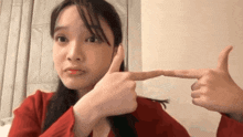 a woman in a red sweater is making a funny face with her fingers .