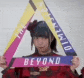 a girl is holding a triangle with a sign that says `` beyond '' .