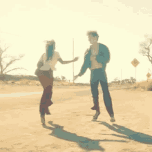 a man and a woman are dancing on the side of a dirt road .