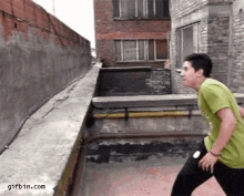 a man in a green shirt is doing a trick on a ledge .