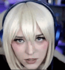 a woman wearing headphones and a blonde wig is making a funny face .