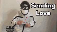 a man in a mask is holding a piece of paper that says sending love on it