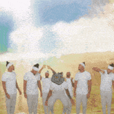 a group of men are standing in a line with a cat on their head