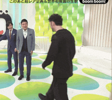 a man in a black sweater is walking in front of two other men in suits