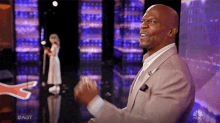 a man in a suit is clapping in front of a girl on a stage