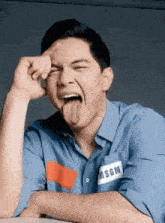 a man wearing a blue shirt is sticking his tongue out .