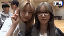 two girls wearing glasses are posing for a picture and one of them is wearing a shirt that says source music