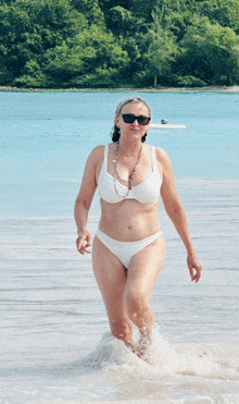 a woman in a white bikini is walking out of the ocean