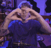 a man wearing glasses and headphones makes a heart with his hands